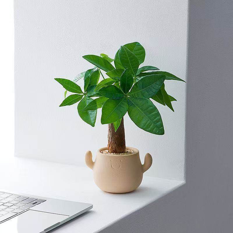 Kunstig grønn plante i dekorativ figurpotte