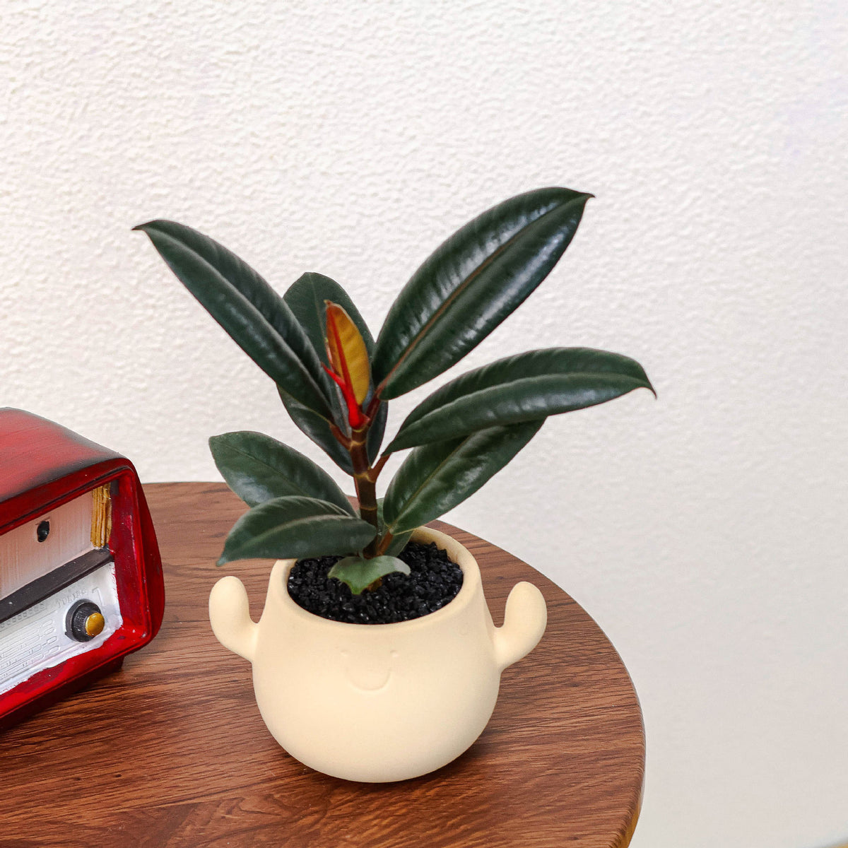 Kunstig grønn plante i dekorativ figurpotte