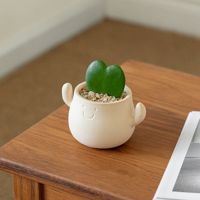 Kunstig grønn plante i dekorativ figurpotte