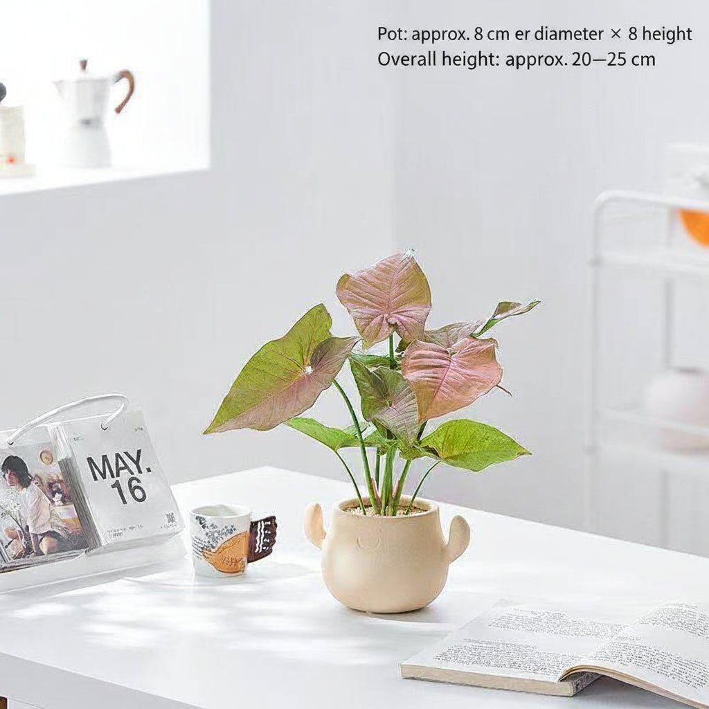 Kunstig grønn plante i dekorativ figurpotte