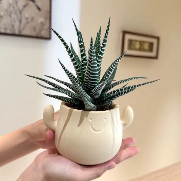 Kunstig grønn plante i dekorativ figurpotte