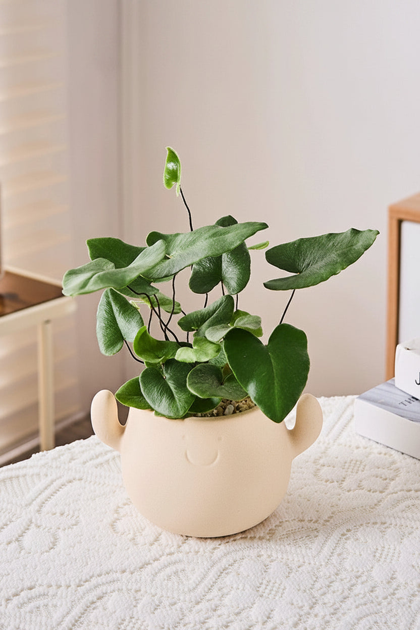 Kunstig grønn plante i dekorativ figurpotte